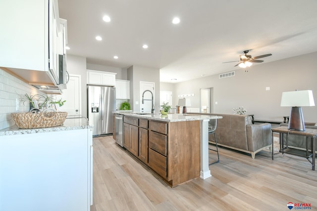 kitchen featuring white cabinetry, sink, a kitchen island with sink, light stone counters, and stainless steel appliances