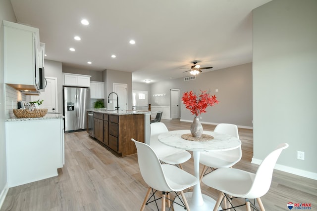 dining space featuring ceiling fan, light hardwood / wood-style floors, and sink