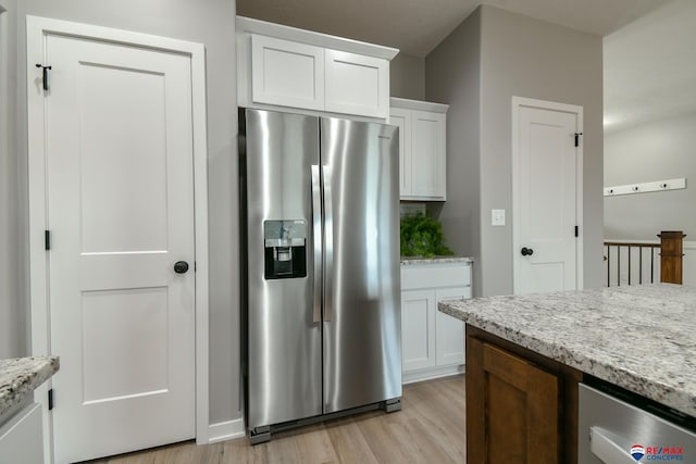 kitchen featuring light wood-type flooring, light stone countertops, stainless steel fridge with ice dispenser, and white cabinets