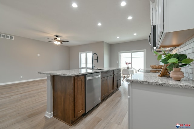 kitchen featuring a center island with sink, sink, stainless steel dishwasher, and light hardwood / wood-style floors