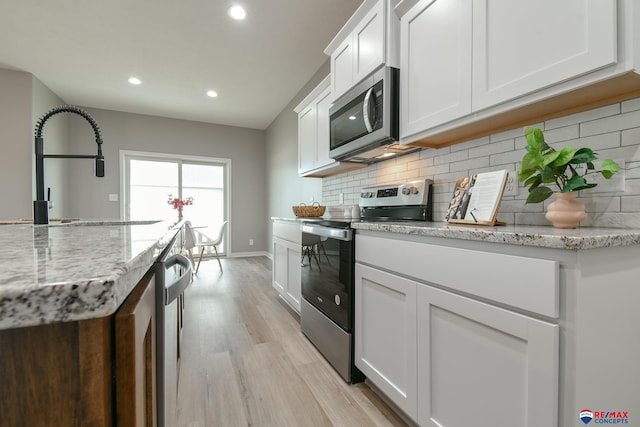 kitchen featuring sink, light stone counters, light hardwood / wood-style flooring, appliances with stainless steel finishes, and white cabinets