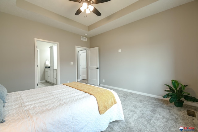 carpeted bedroom with ceiling fan, connected bathroom, and a raised ceiling