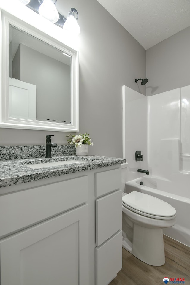 full bathroom featuring hardwood / wood-style flooring, vanity, toilet, and shower / bathing tub combination