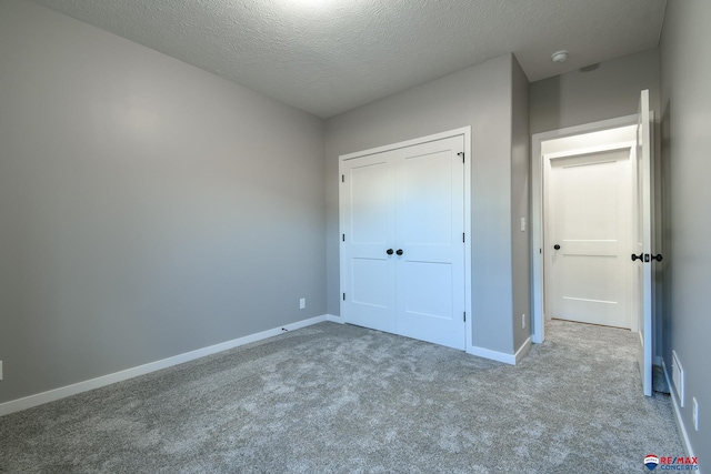 unfurnished bedroom with light colored carpet, a closet, and a textured ceiling