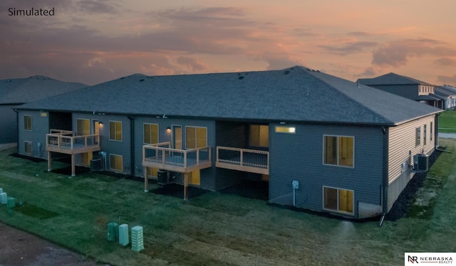 back house at dusk featuring a wooden deck, a yard, and central AC unit