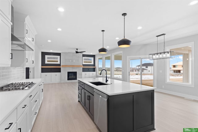 kitchen featuring sink, stainless steel appliances, an island with sink, white cabinets, and decorative light fixtures