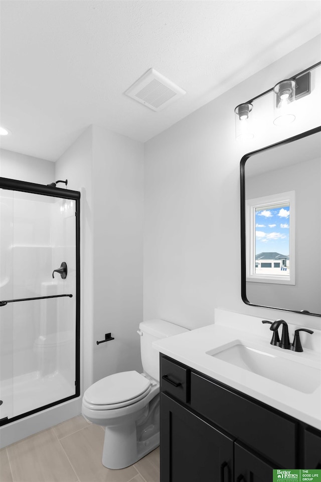 bathroom with vanity, tile patterned floors, a shower with door, and toilet