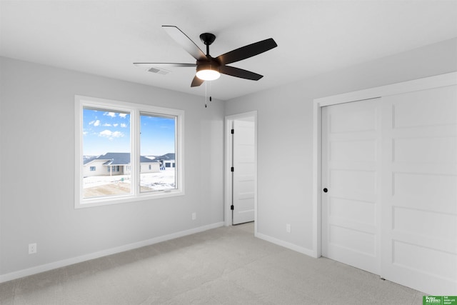 unfurnished bedroom with light colored carpet, a closet, and ceiling fan