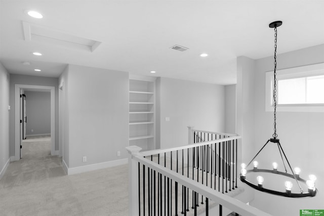 hallway featuring a chandelier and light carpet