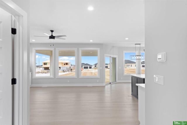 living room with ceiling fan with notable chandelier and light hardwood / wood-style floors