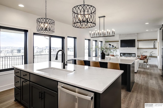 kitchen featuring stainless steel dishwasher, a kitchen island with sink, and sink