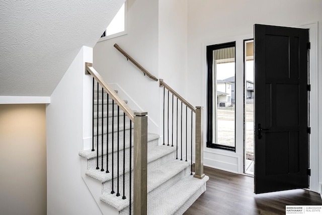 foyer with lofted ceiling, dark hardwood / wood-style floors, and a textured ceiling