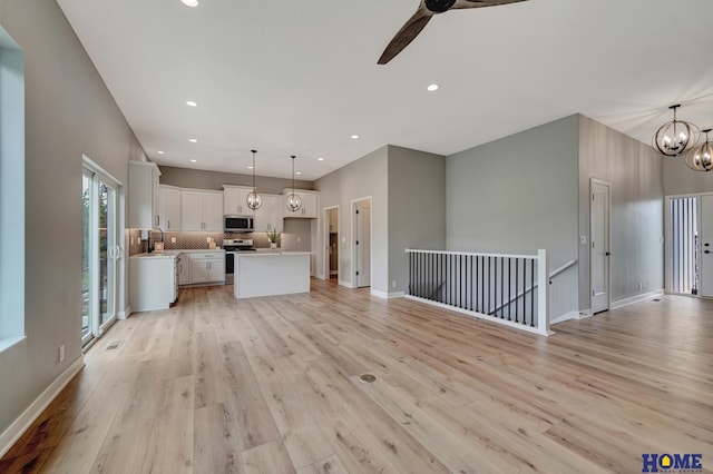 unfurnished living room featuring sink, ceiling fan with notable chandelier, and light hardwood / wood-style flooring