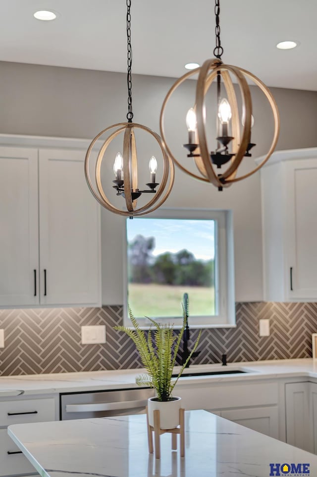 kitchen with tasteful backsplash, pendant lighting, white cabinetry, and a chandelier