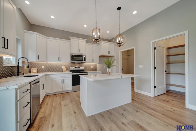 kitchen featuring sink, hanging light fixtures, appliances with stainless steel finishes, a kitchen island, and white cabinets