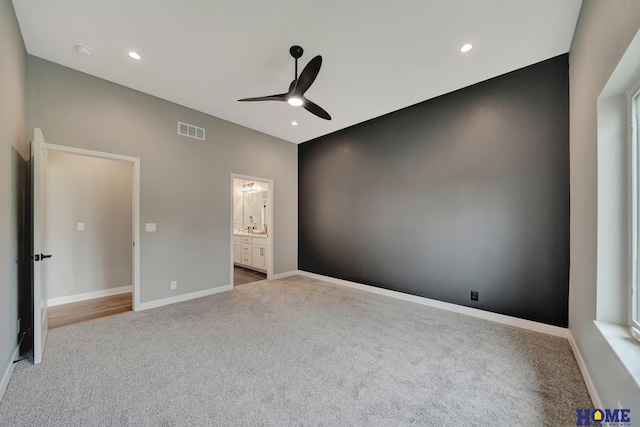 unfurnished bedroom featuring light carpet, connected bathroom, and ceiling fan