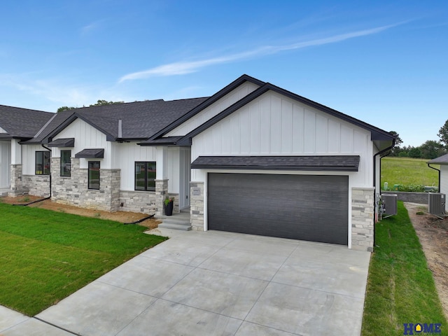 view of front of house featuring a garage, a front yard, and central air condition unit