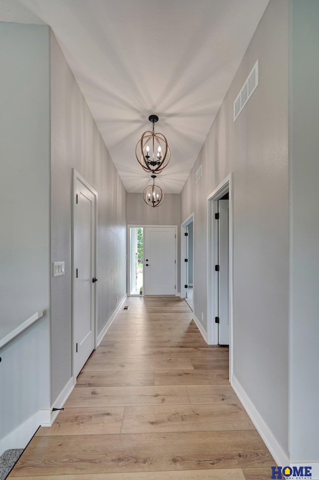 corridor featuring an inviting chandelier and light wood-type flooring