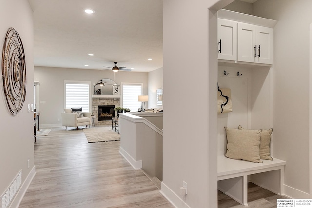 mudroom featuring a fireplace, ceiling fan, and light hardwood / wood-style floors