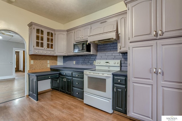 kitchen with premium range hood, decorative backsplash, electric range, light hardwood / wood-style floors, and a textured ceiling