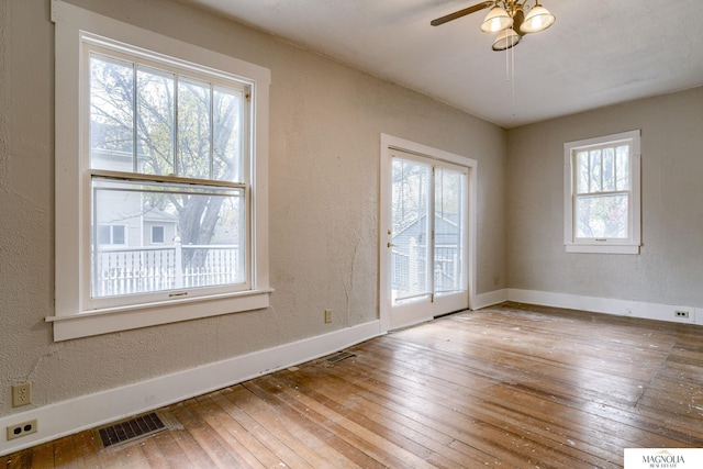 empty room with ceiling fan, a healthy amount of sunlight, and wood-type flooring