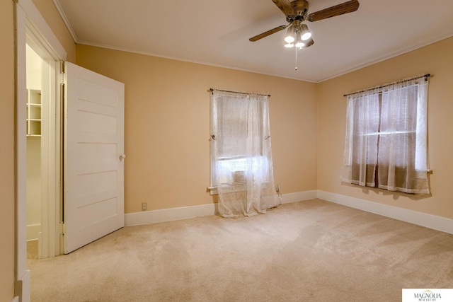 spare room with ceiling fan, ornamental molding, and light carpet