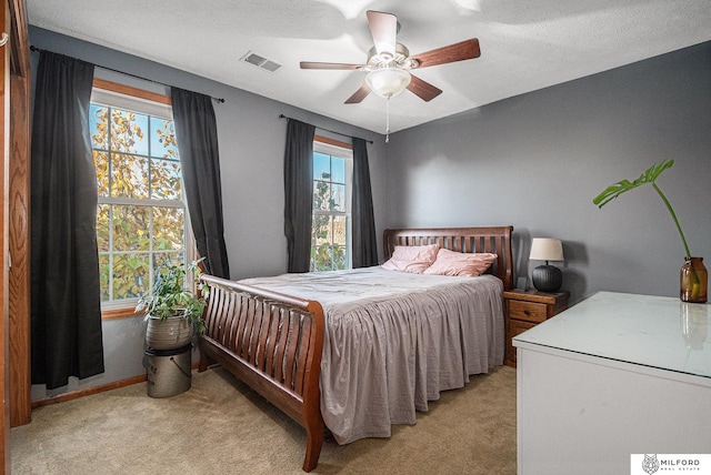 carpeted bedroom with ceiling fan and a textured ceiling