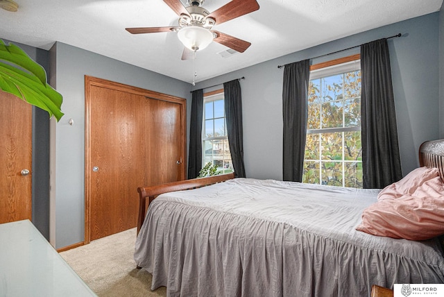 carpeted bedroom with ceiling fan and a closet