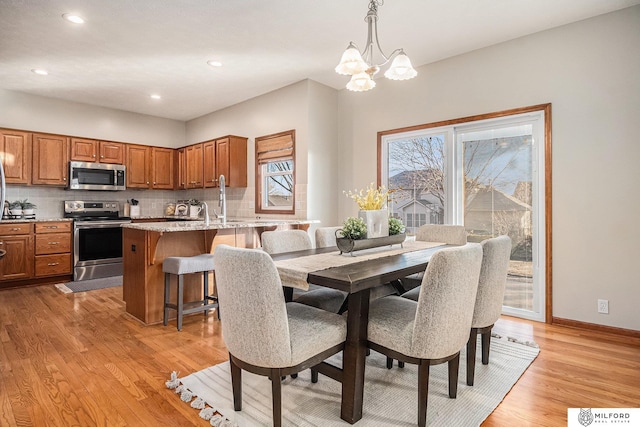 dining space featuring an inviting chandelier, sink, and light wood-type flooring