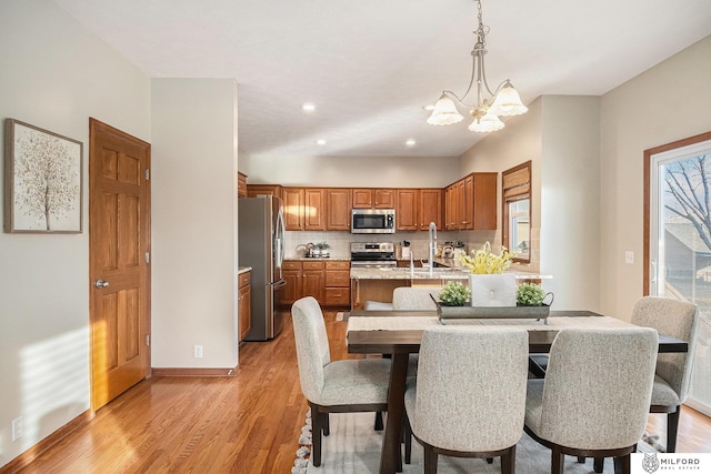 dining room featuring sink, light hardwood / wood-style flooring, and a notable chandelier