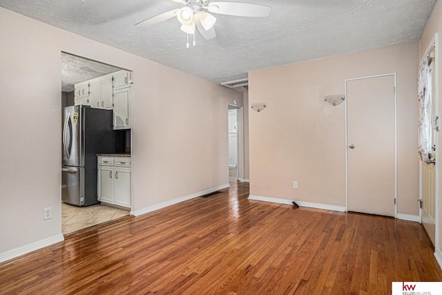 unfurnished living room with ceiling fan, a textured ceiling, and light wood-type flooring