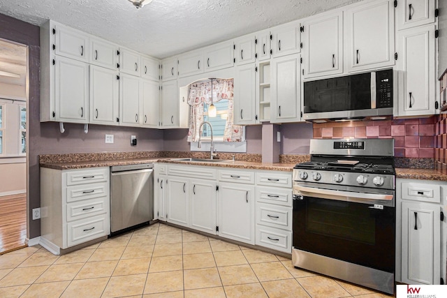 kitchen featuring white cabinetry, sink, light tile patterned flooring, and appliances with stainless steel finishes