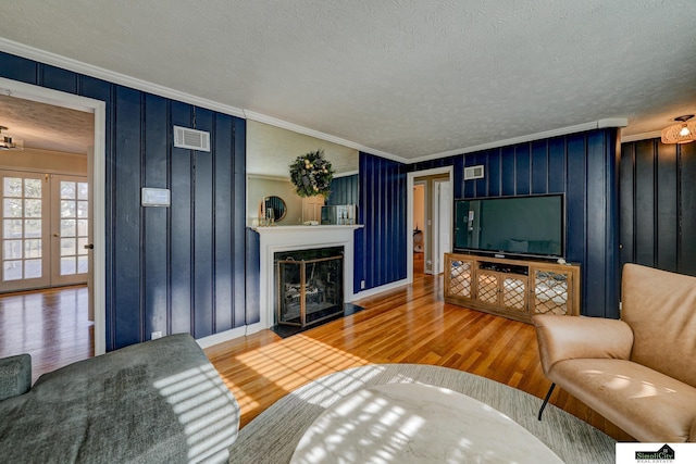 living room with ornamental molding, wood-type flooring, a textured ceiling, and french doors