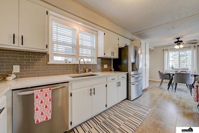 kitchen with stainless steel appliances, sink, white cabinets, and decorative backsplash