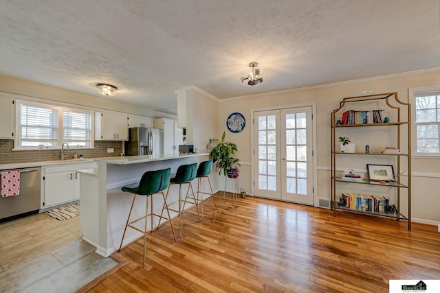 kitchen featuring appliances with stainless steel finishes, a breakfast bar area, white cabinets, and kitchen peninsula