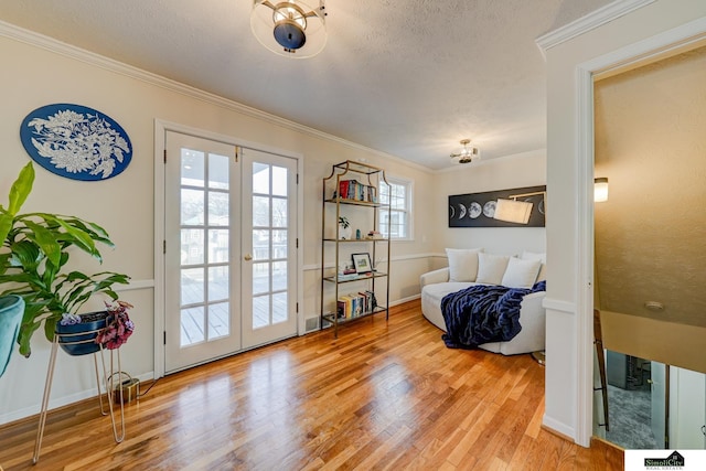 living area featuring hardwood / wood-style flooring, crown molding, a textured ceiling, and french doors