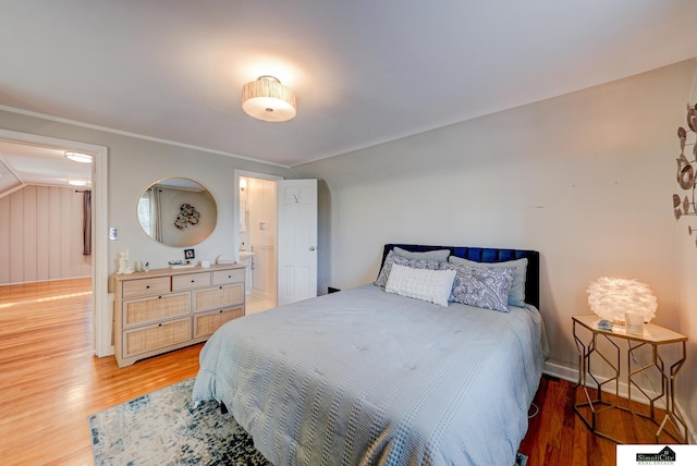 bedroom with wood-type flooring, ornamental molding, and ensuite bathroom