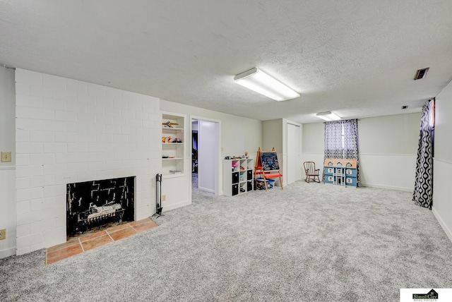 game room with a brick fireplace, carpet floors, and a textured ceiling