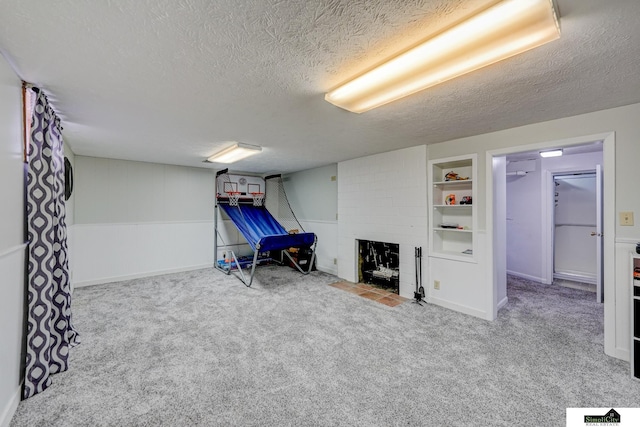 basement with carpet floors, a fireplace, a textured ceiling, and built in shelves