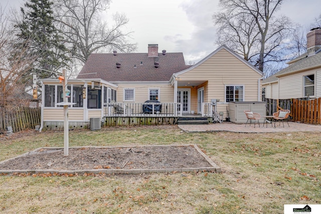 rear view of house with a lawn, a wooden deck, a patio area, a sunroom, and a hot tub