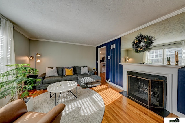 living room with hardwood / wood-style floors, ornamental molding, and a textured ceiling