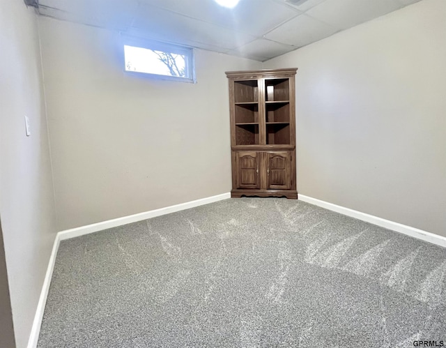 basement with a paneled ceiling and carpet flooring