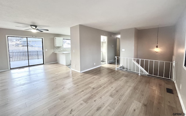 unfurnished living room featuring ceiling fan and light wood-type flooring