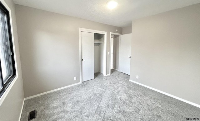 unfurnished bedroom with light colored carpet, a textured ceiling, and a closet