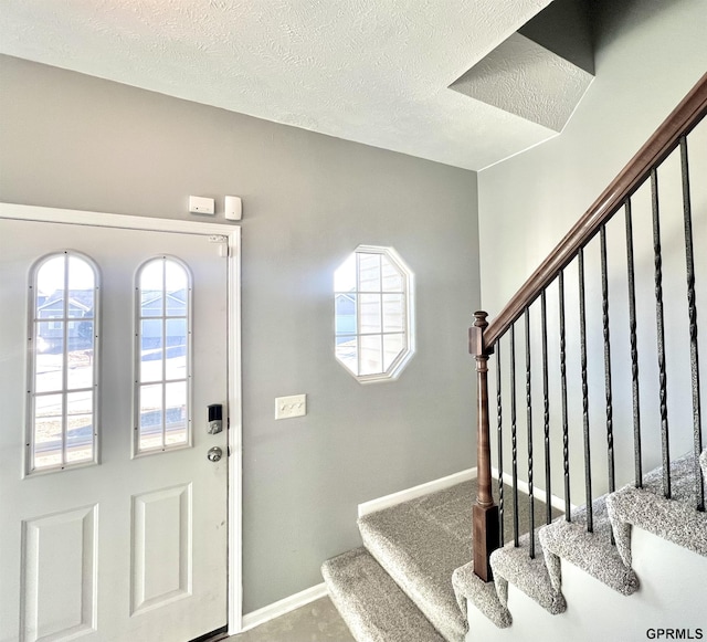 foyer entrance featuring carpet and a textured ceiling