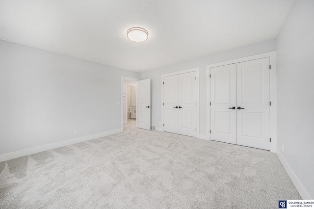 unfurnished bedroom featuring multiple closets and light carpet