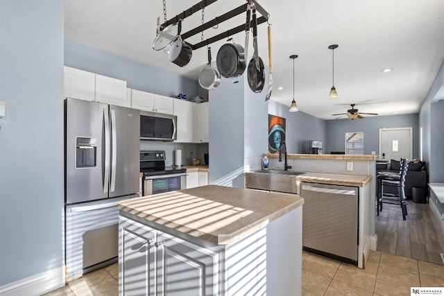 kitchen with stainless steel appliances, sink, a kitchen island, and white cabinets