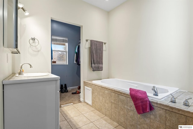 bathroom with vanity, tile patterned flooring, and tiled tub