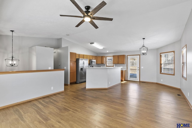 kitchen featuring pendant lighting, hardwood / wood-style flooring, vaulted ceiling, and stainless steel appliances