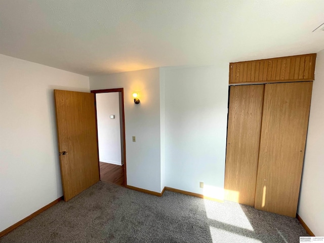 unfurnished bedroom featuring dark carpet and a closet